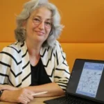 Portret van Monica met een laptop, zij is zakelijk tekenaar en weet ingewikkelde vraagstukken te vertalen naar aansprekende tekeningen
